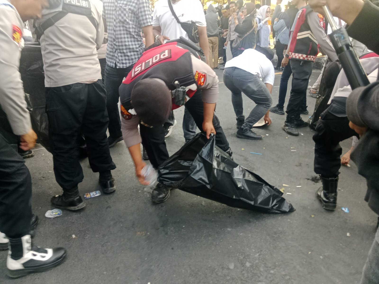 Peserta unjuk rasa bersama personel Polresta Gowa membersihkan sampah yang berserakan di depan Kantor Bupati Gowa setelah aksi penyampaian aspirasi berakhir, Jumat (28/8/2026) sore. (Foto: RujukanNews)